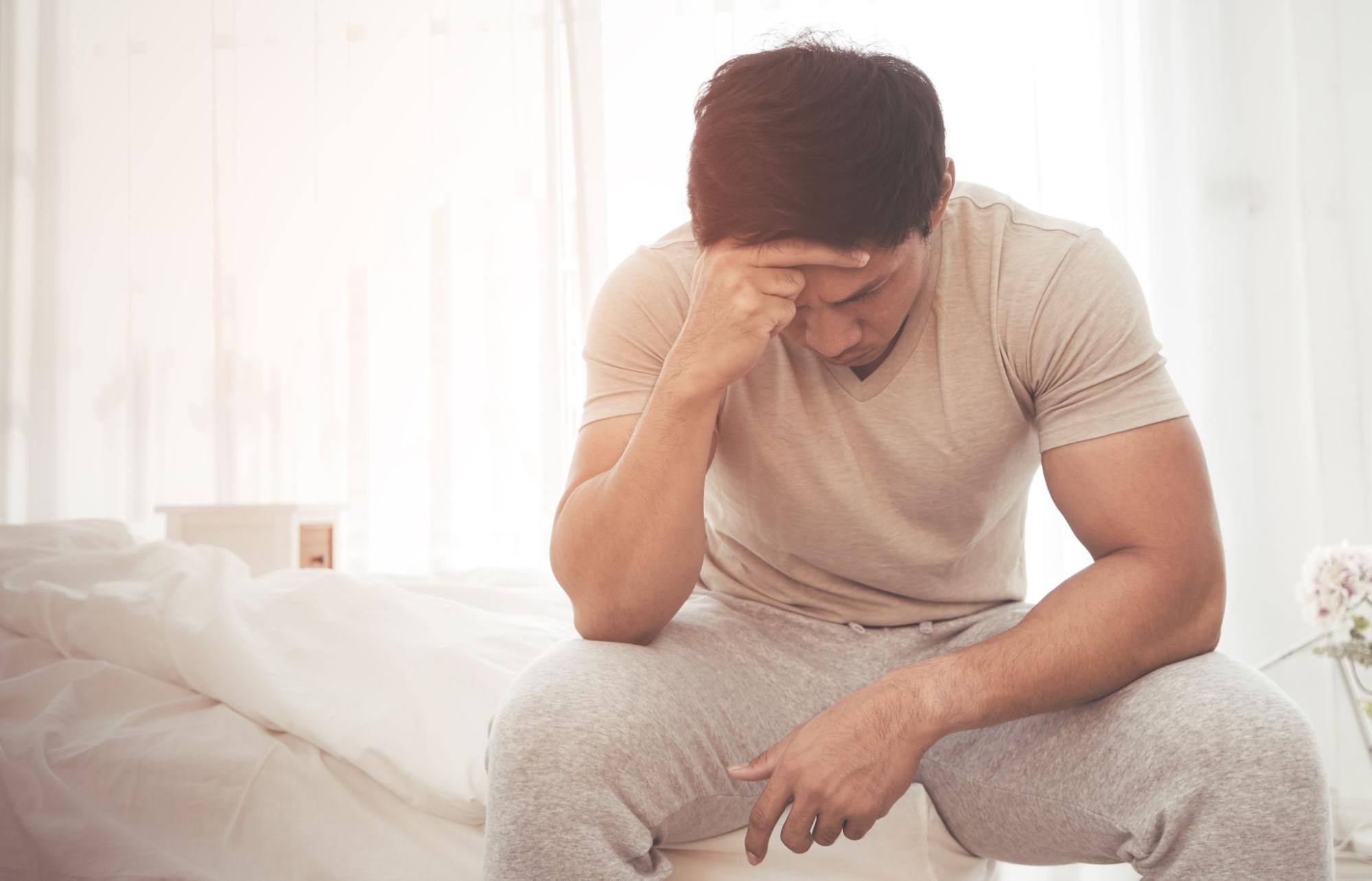 Man sitting on bed feeling depressed