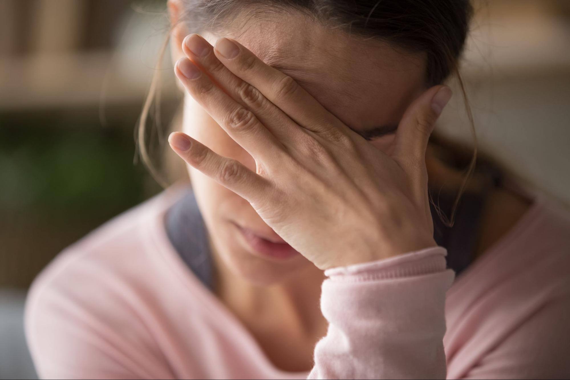 Woman putting hand over her eyes looking depressed